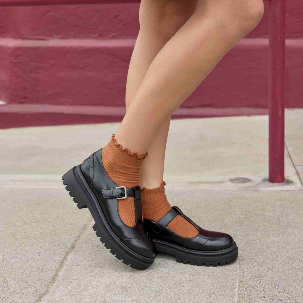 Image 3: Dalma Black Chunky Mary Jane Shoes in black worn with ankle socks, lifestyle side view showing chunky sole and T-bar shape